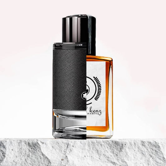 "Two perfume bottles are displayed side by side on a white marble surface, with a soft pink background highlighting their designs."
"On the left, a black-colored bottle labeled Explorer Montblanc."
"The Explorer Montblanc bottle has a sleek, modern design with a deep black color and subtle, sophisticated details."
"On the right, an amber-colored bottle, the Baytulkenz inspired version of Explorer Montblanc."
"The Baytulkenz bottle features a warm, amber hue with a minimalist design and the Baytulkenz logo."